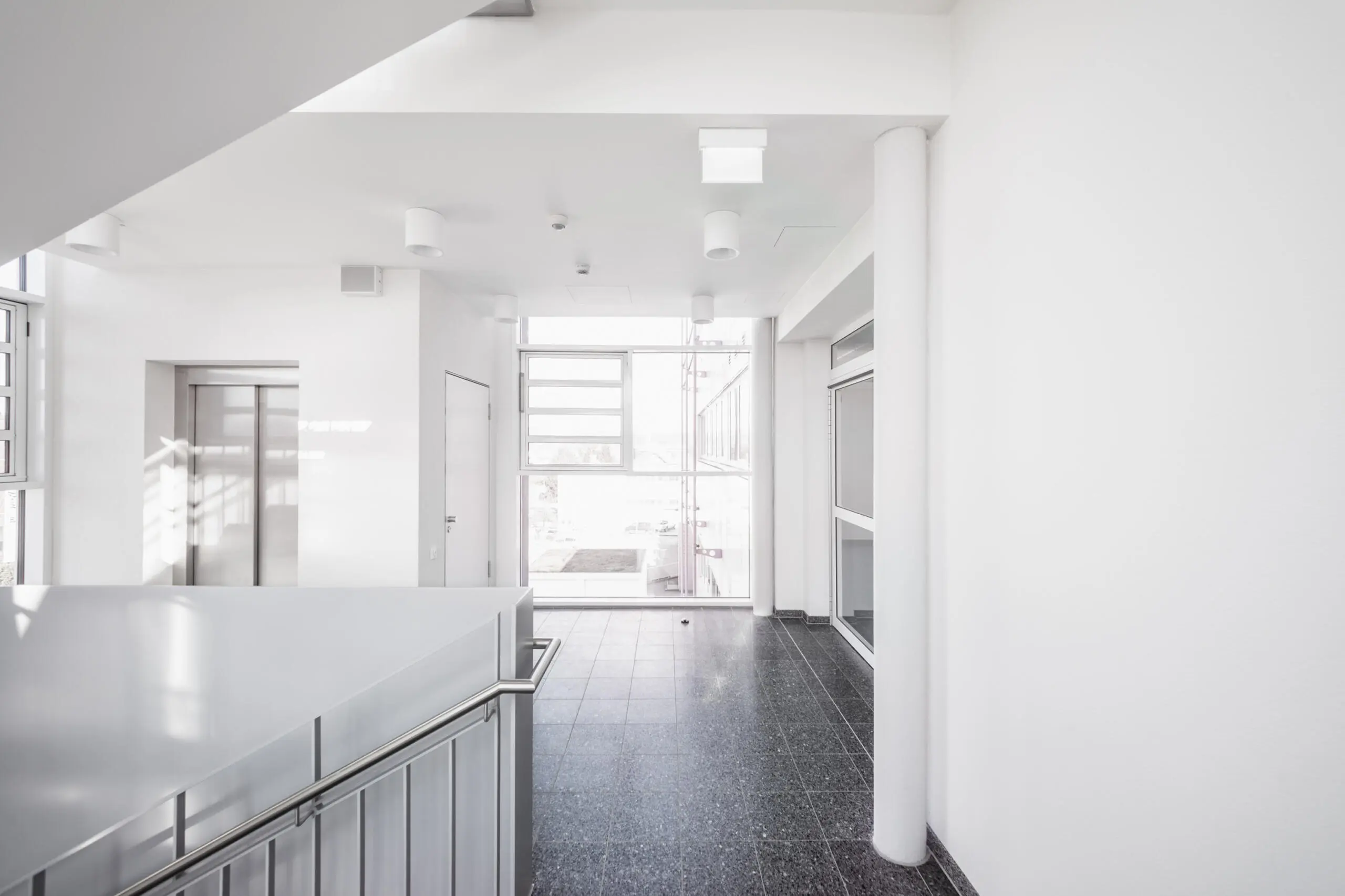 Heller Eingangsbereich mit Aufzug und Fensterfront, Architekturfotografie.