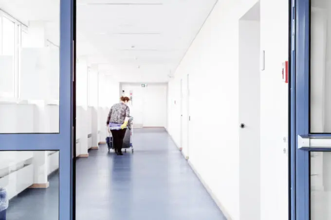 Unternehmensfotografie: Flur mit Reinigungskraft und Wagen in hellem Gebäude.