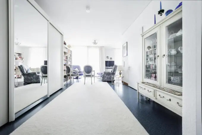 Weißer Teppich führt in hellen, einladenden Wohnraum mit Antiquitäten.