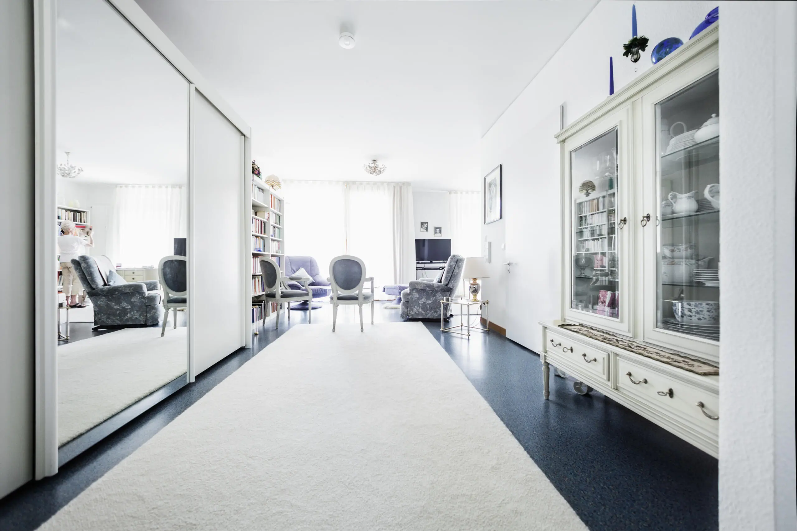 Weißer Teppich führt in hellen, einladenden Wohnraum mit Antiquitäten.