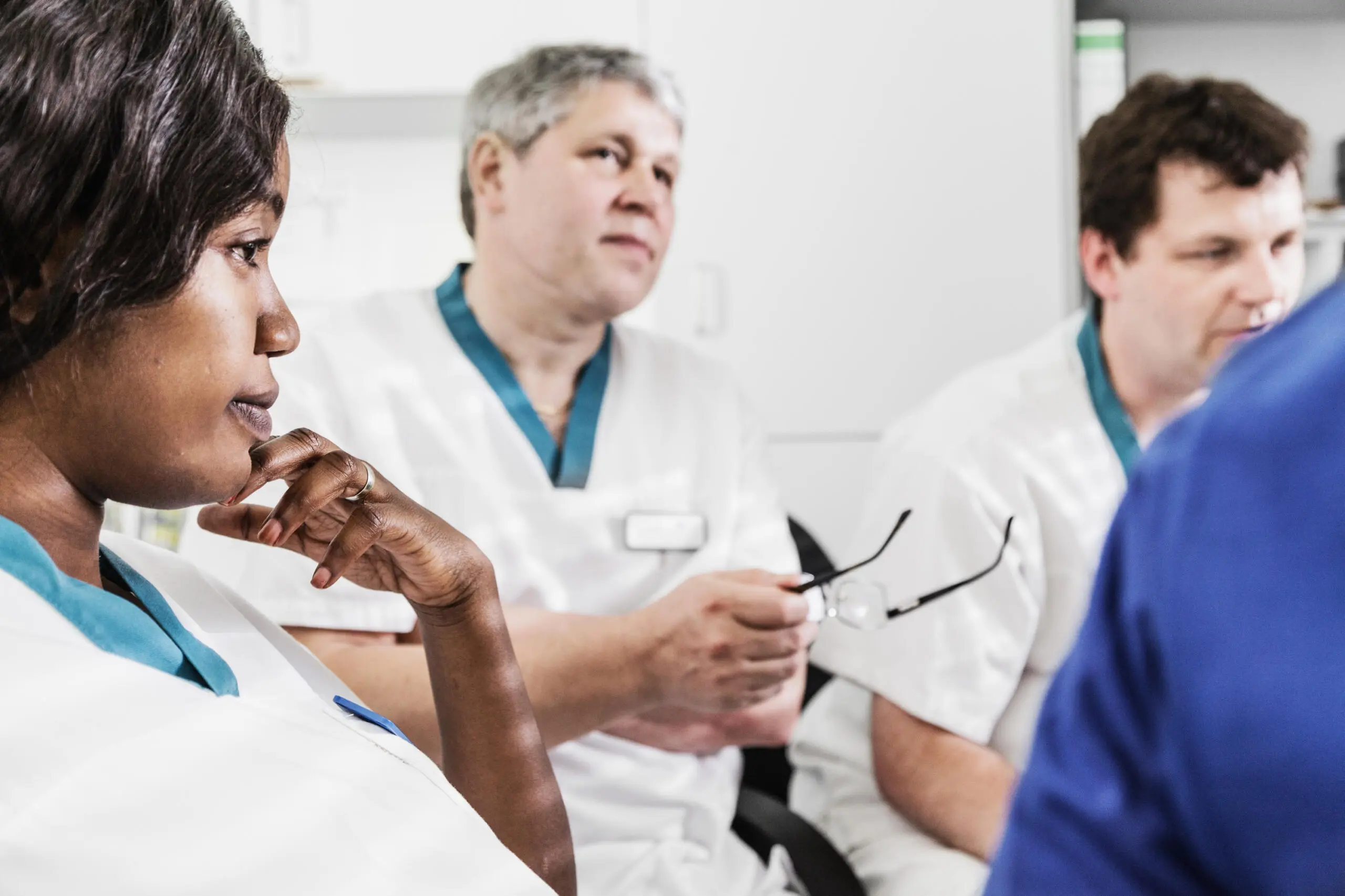 Ärzte in Besprechung, Fokus auf nachdenkliche Ärztin im Vordergrund.