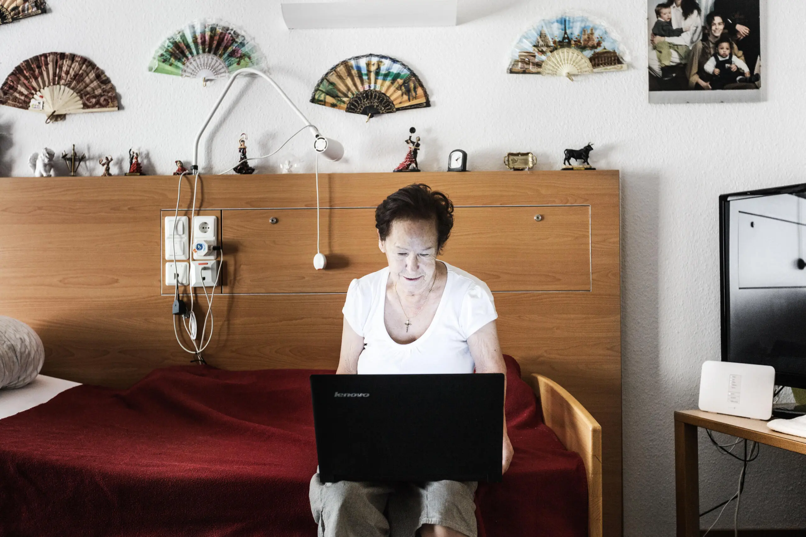 Ältere Frau mit Laptop im Krankenhauszimmer.