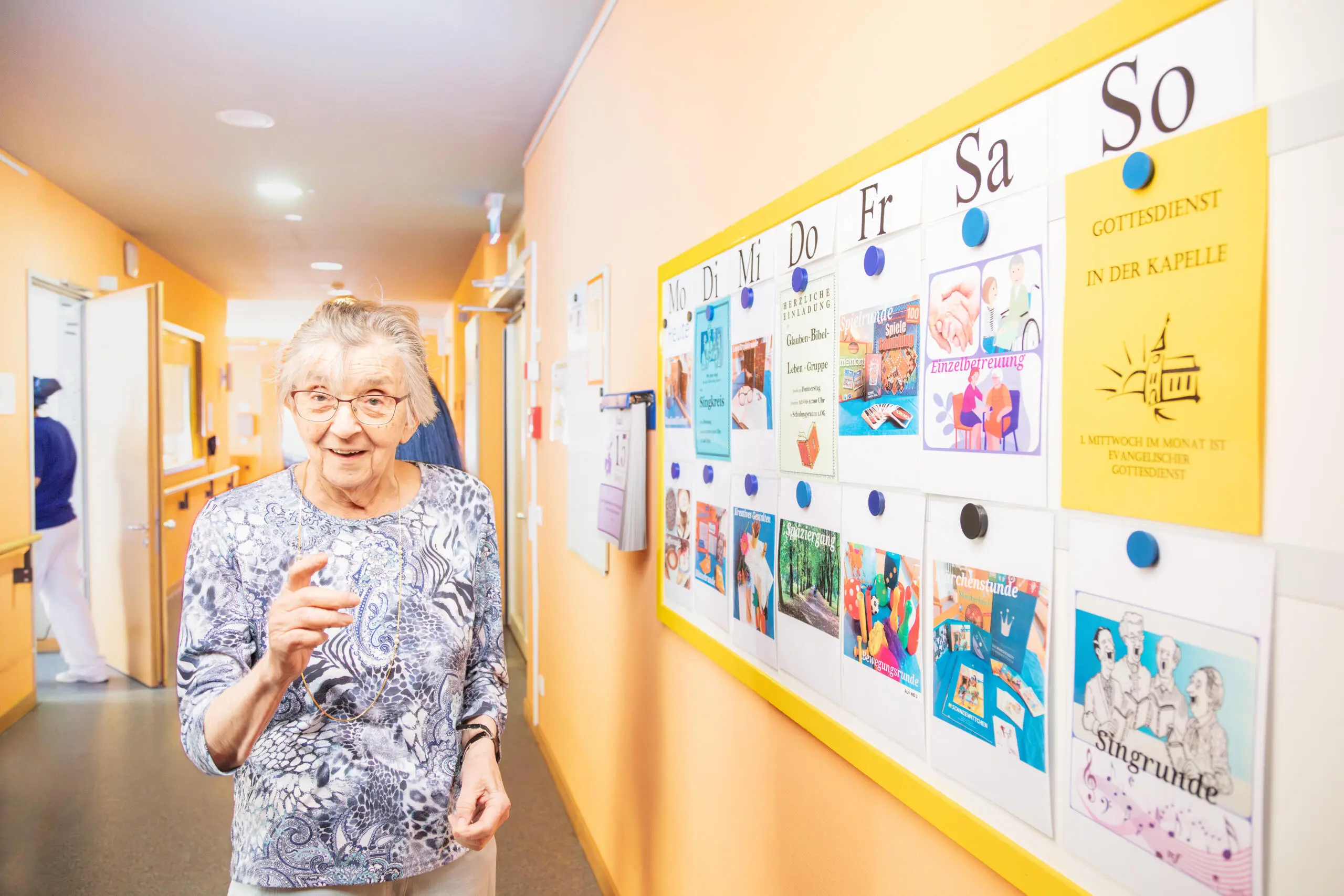 Eine ältere Dame in einem hellen, freundlichen Flur.