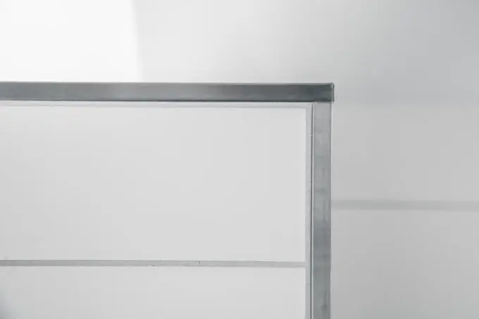 Nahaufnahme einer Fliesenecke mit quadratischem Edelstahl-Abschlussprofil und weißen Wandfliesen