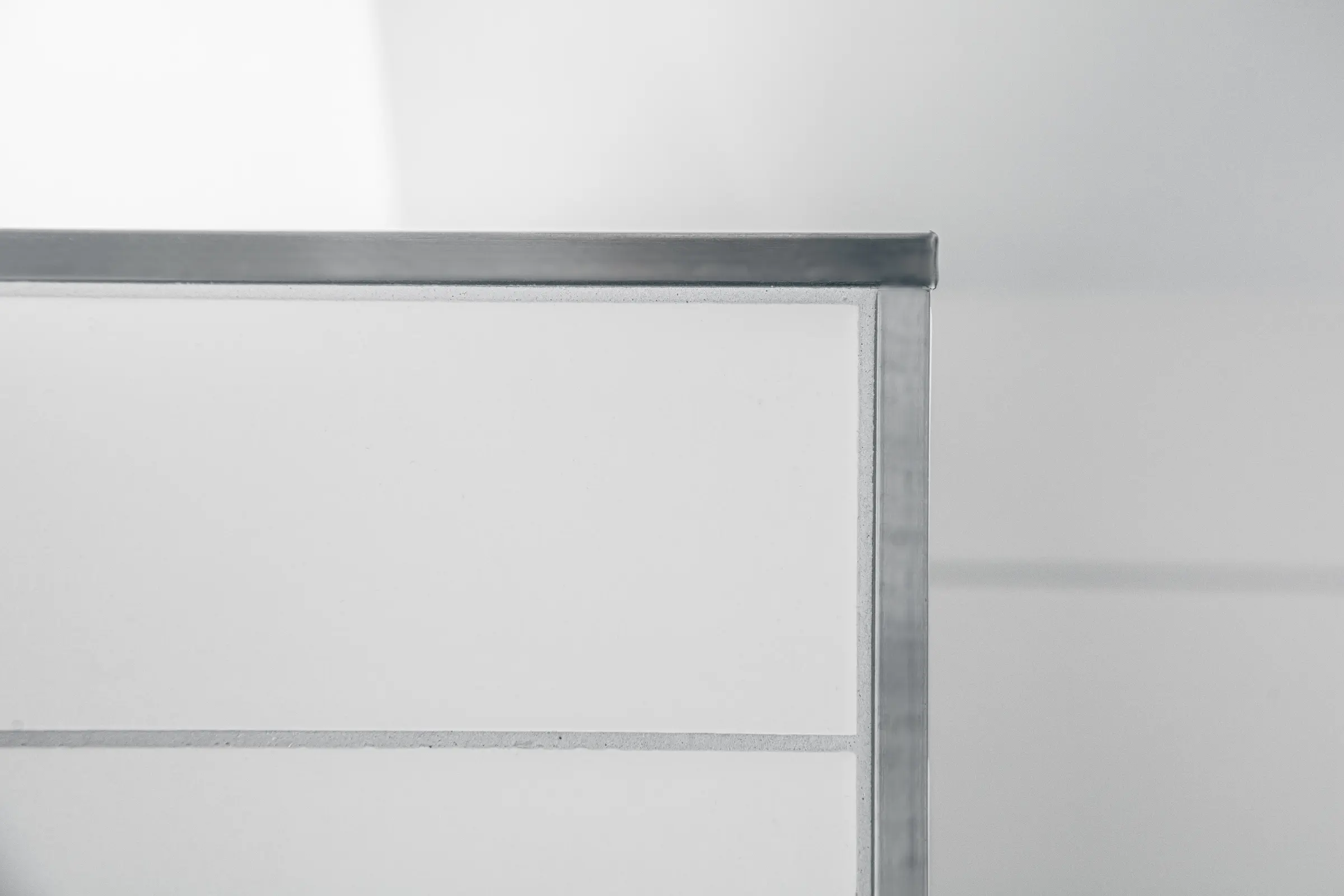 Nahaufnahme einer Fliesenecke mit quadratischem Edelstahl-Abschlussprofil und weißen Wandfliesen