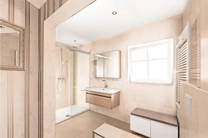 Modernes Badezimmer mit beigen Wand- und Bodenfliesen, Glasdusche und Waschtisch