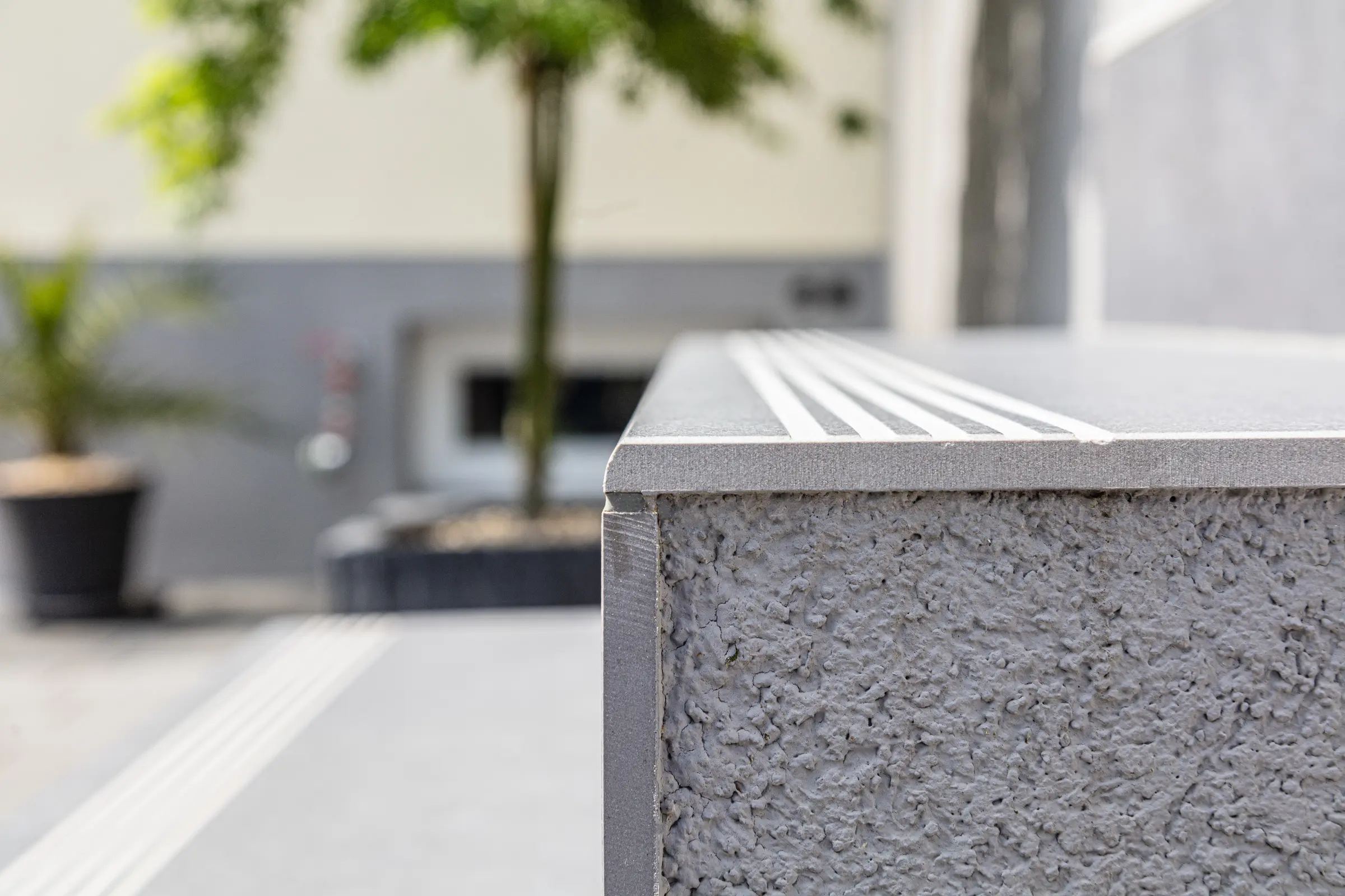 Detailansicht einer grauen Stufenkante mit drei eingefrästen Rillen zur Rutschhemmung