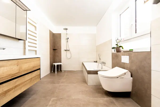 Modernes Badezimmer mit großformatigen braunen Bodenfliesen und beigen Wandfliesen, ebenerdiger Dusche und Badewanne