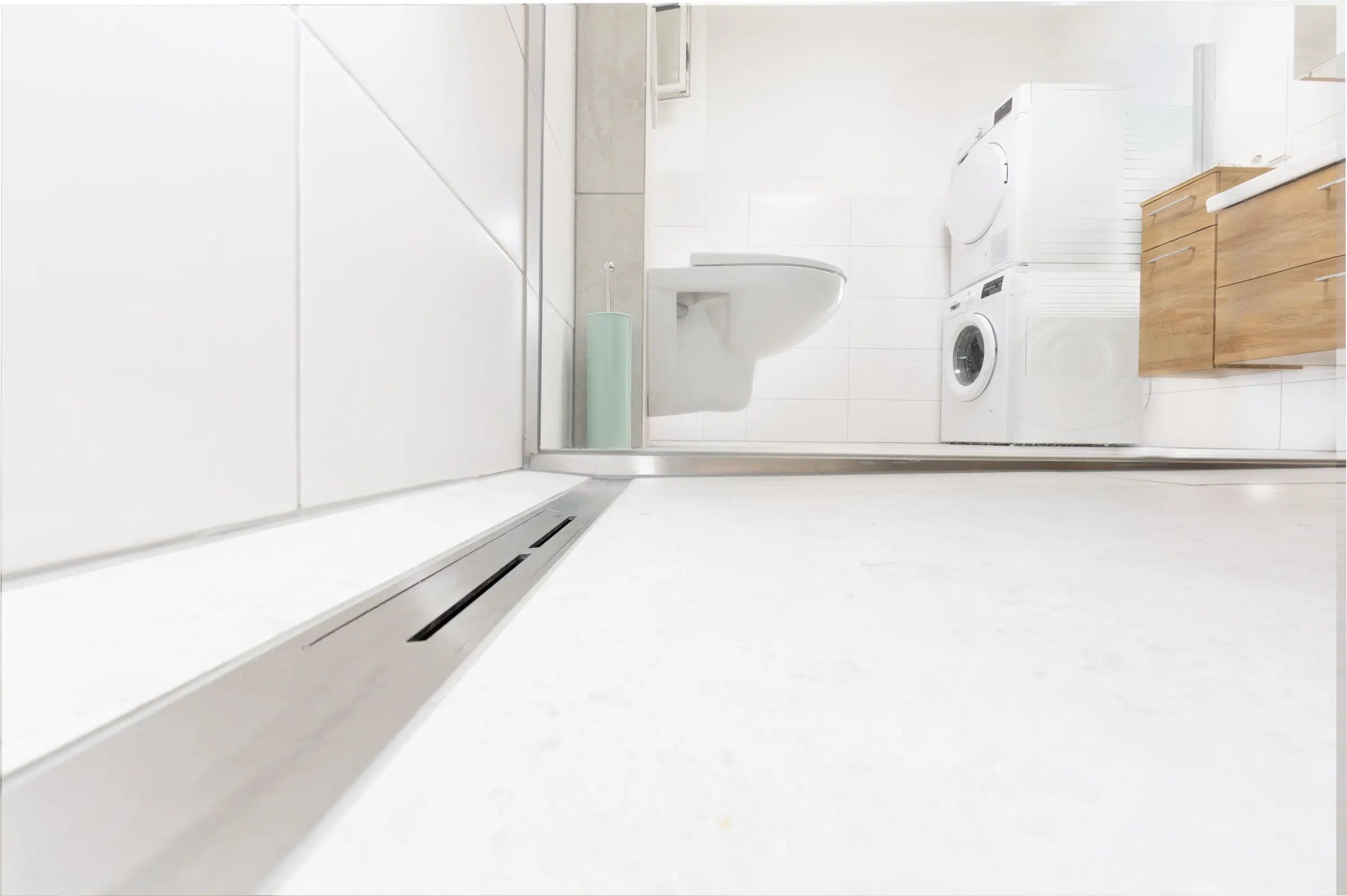 Detailansicht einer Edelstahl-Duschrinne in bodengleicher Dusche mit Blick auf WC und Waschbereich