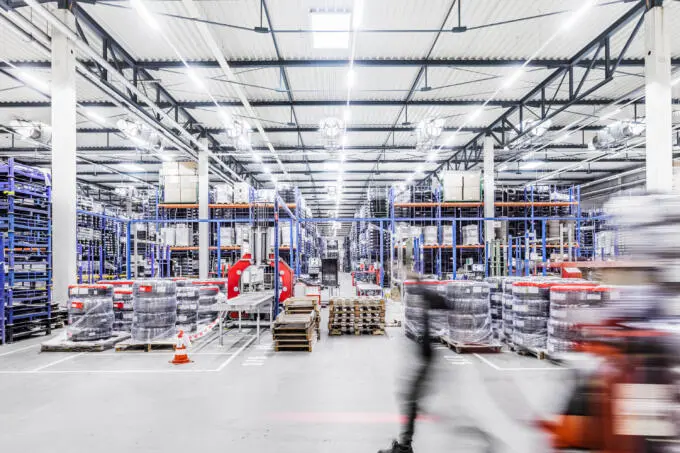 Innenansicht einer Lagerhalle mit Hochregalen und Bewegungsunschärfe im Vordergrund