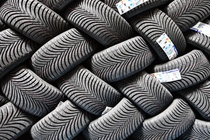 Detailansicht gestapelter neuer Winterreifen mit V-Profil und Etiketten im Lager