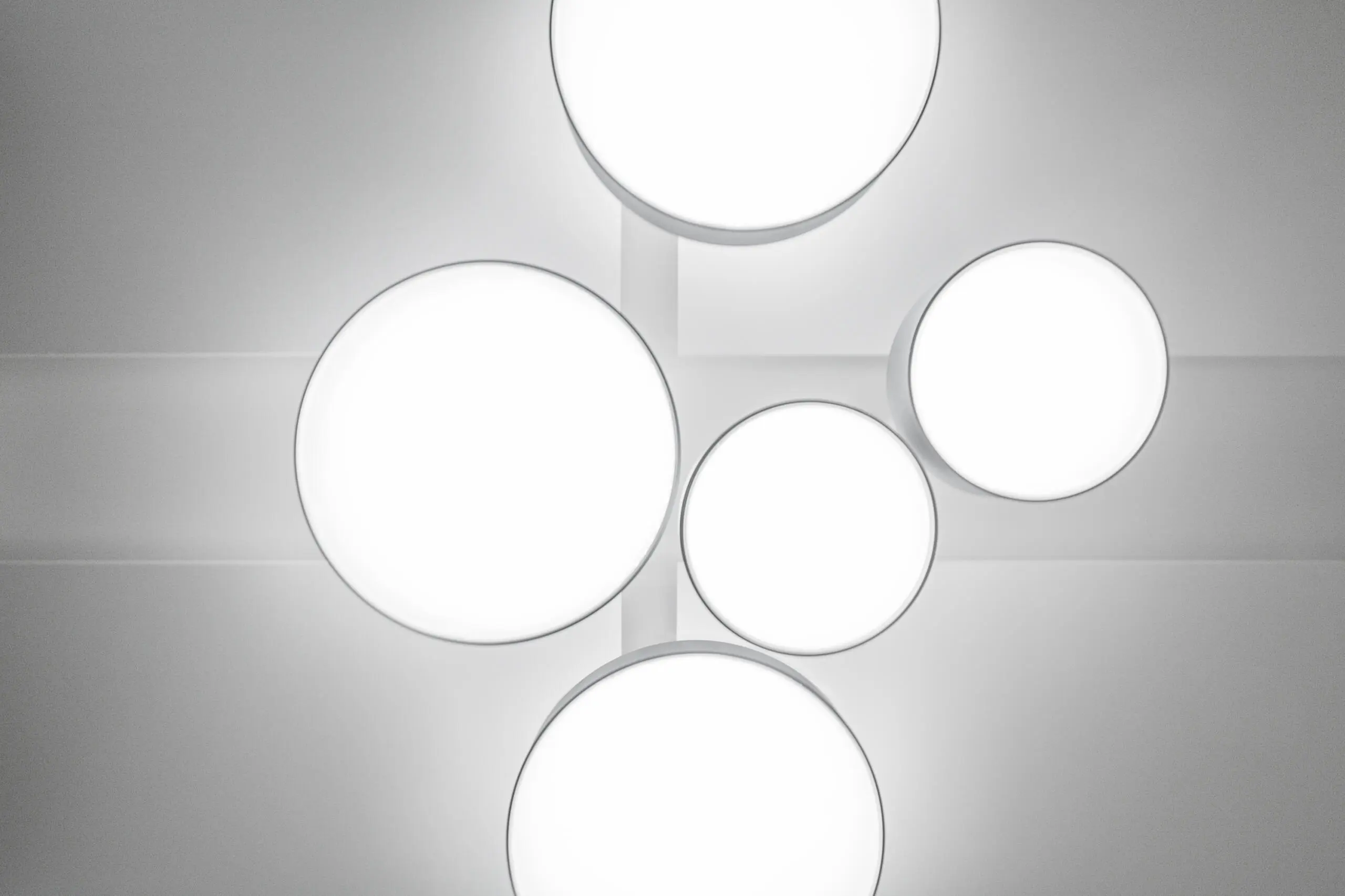 Abstrakte Ansicht runder weißer Deckenleuchten in minimalistischer Anordnung an einer grauen Decke