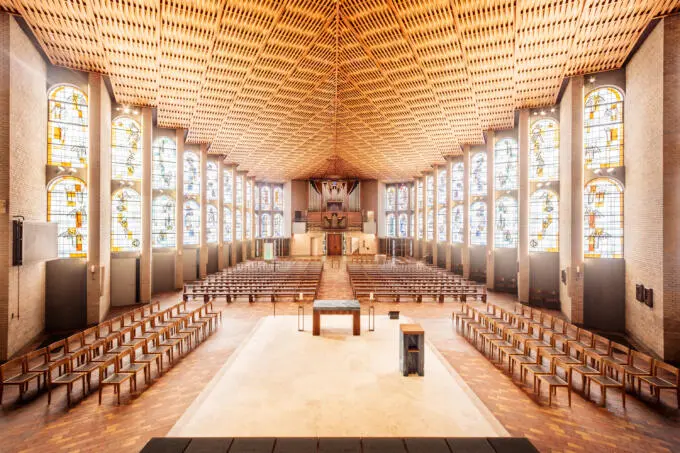 Innenansicht einer modernen Kirche mit Backsteinwänden und geometrischer Holzdecke aus erhöhter Perspektive