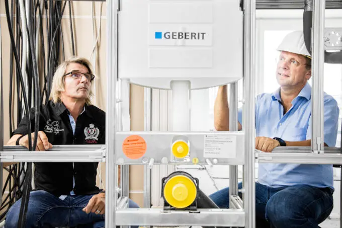 Zwei Handwerker bei der Begutachtung eines Sanitär-Installationsrahmens auf einer Baustelle