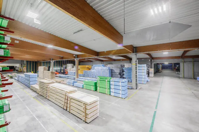 Lagerhalle mit Holzstapeln, Gabelstapler im Hintergrund. Unternehmensfotografie Karlsruhe.