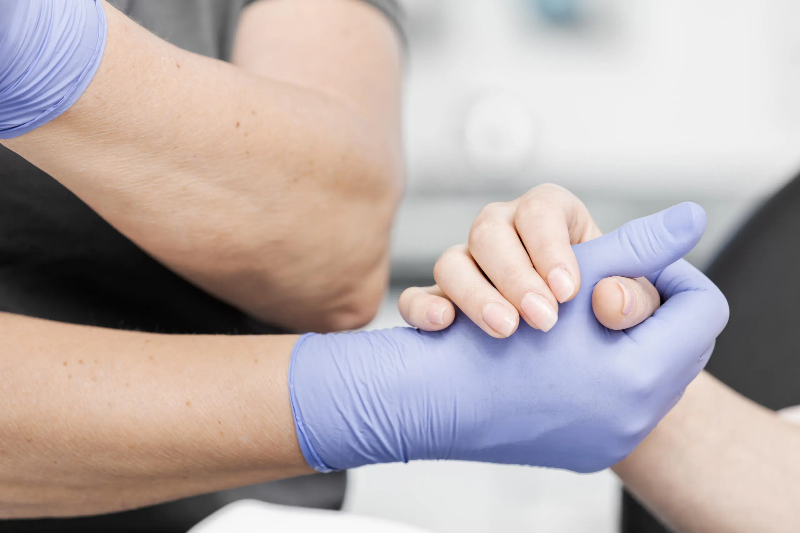 Nahaufnahme einer Hand mit blauem medizinischen Handschuh im Kontakt mit einer Patientenhand